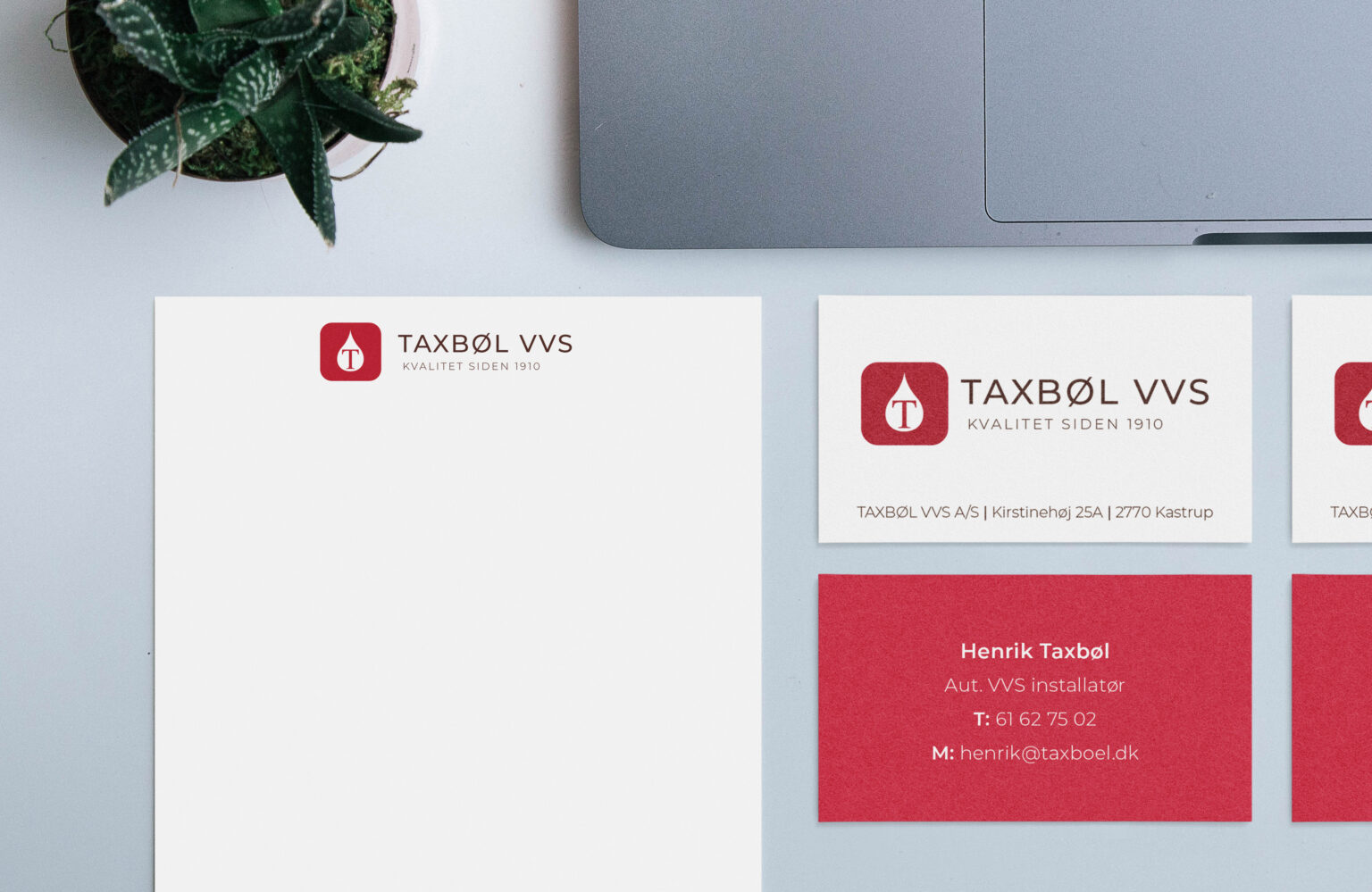 Taxbøl VVS visitkort og brevpapir på et bord med en MacBook og en plante